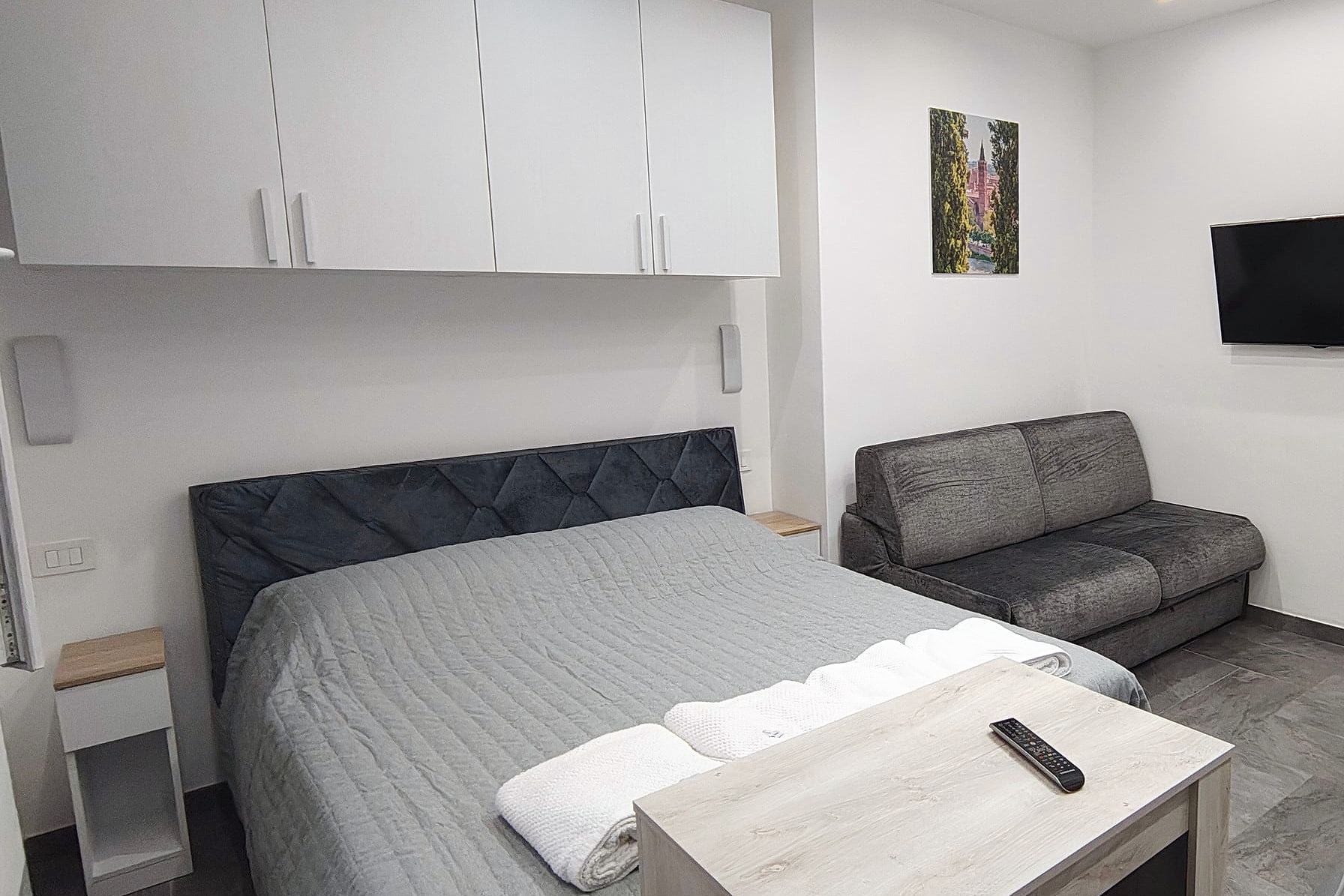 Letto matrimoniale, tavolino in rovere, divano letto e televisore nella camera quadrupla