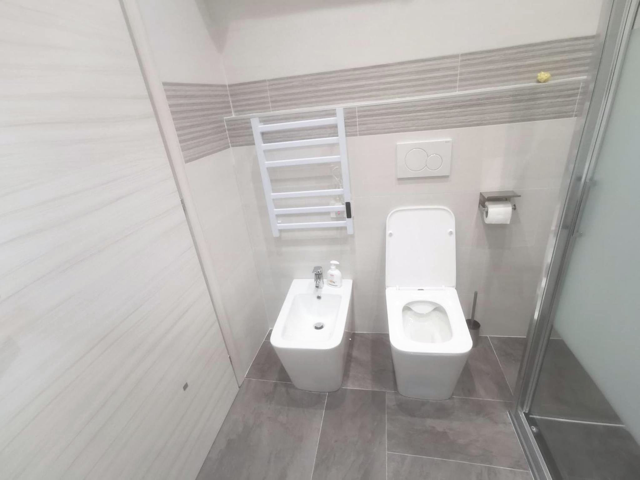 Bagno del monolocale con WC, bidet, doccia con vetro satinato e termoarredo