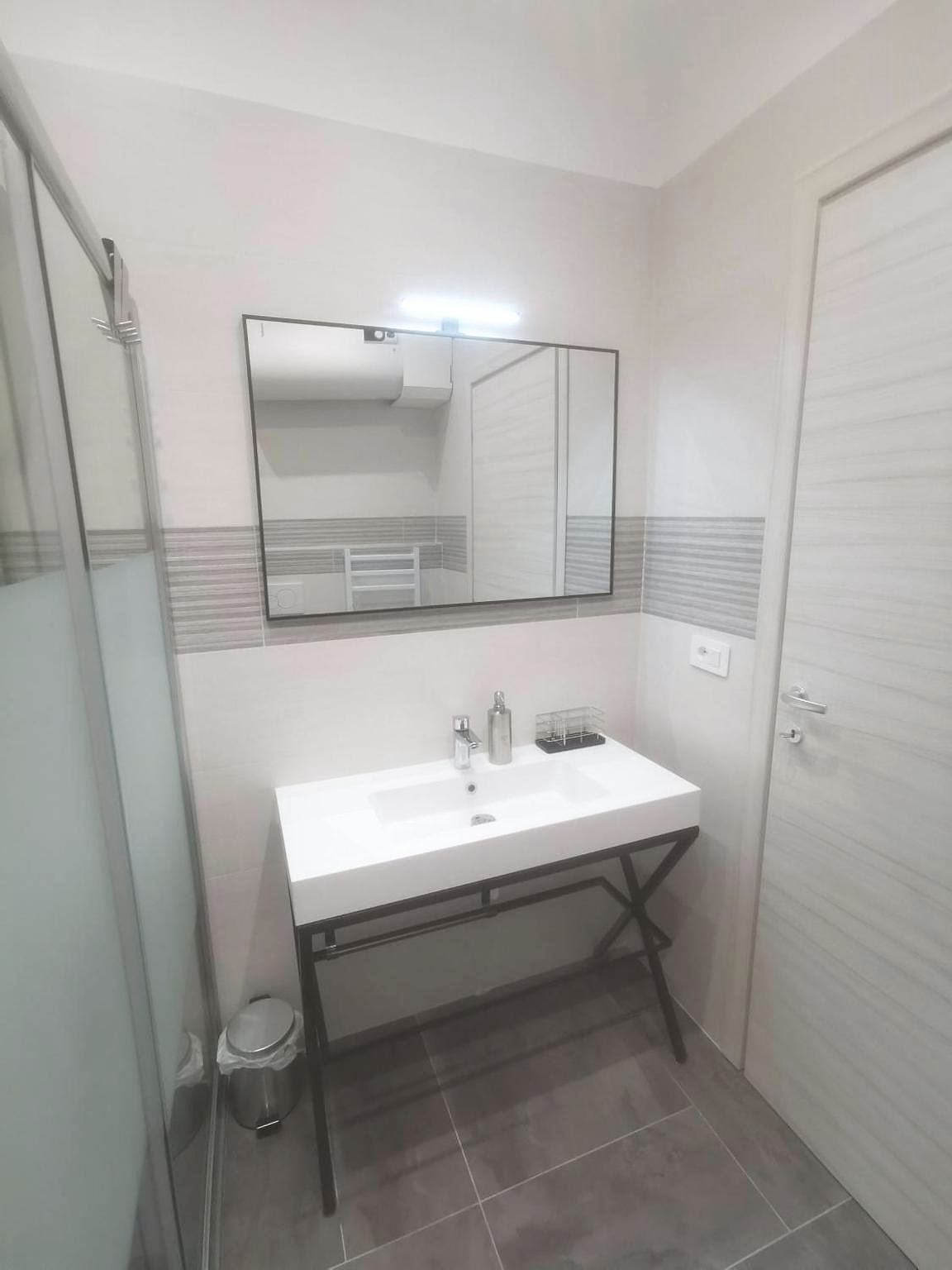 Lavabo su struttura metallica nera e specchio nel bagno del monolocale
