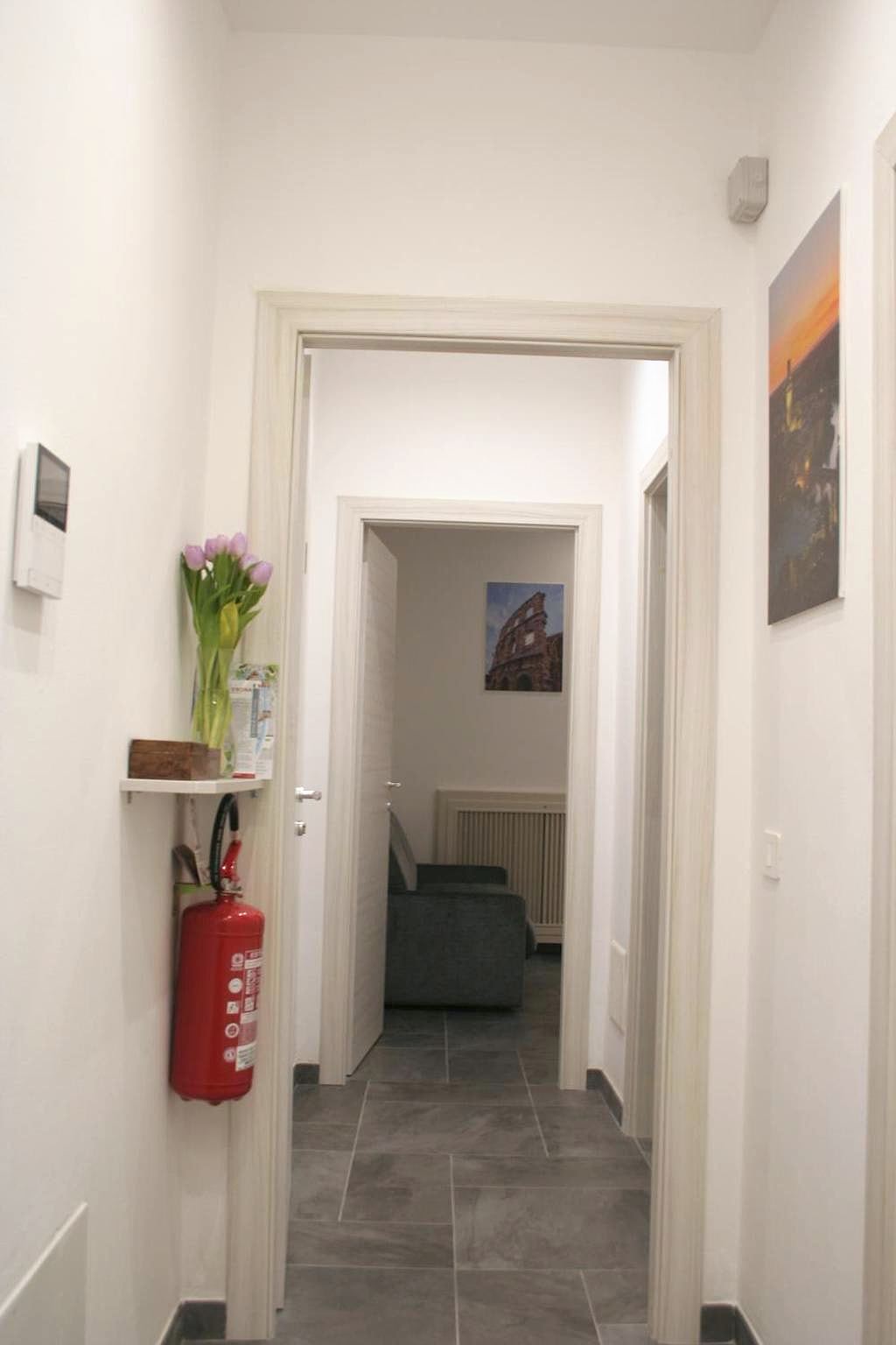 Corridoio bianco dell’ingresso in comune con videocitofono, quadri e mensola